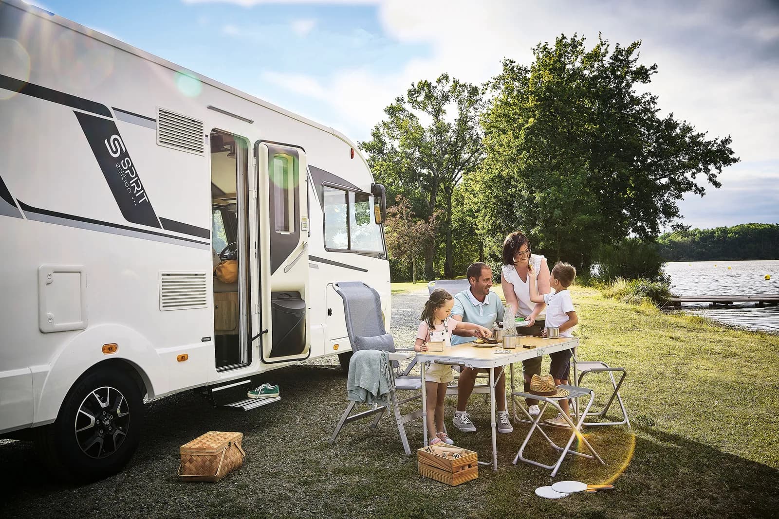Familj som fikar utanför en husbil på camping